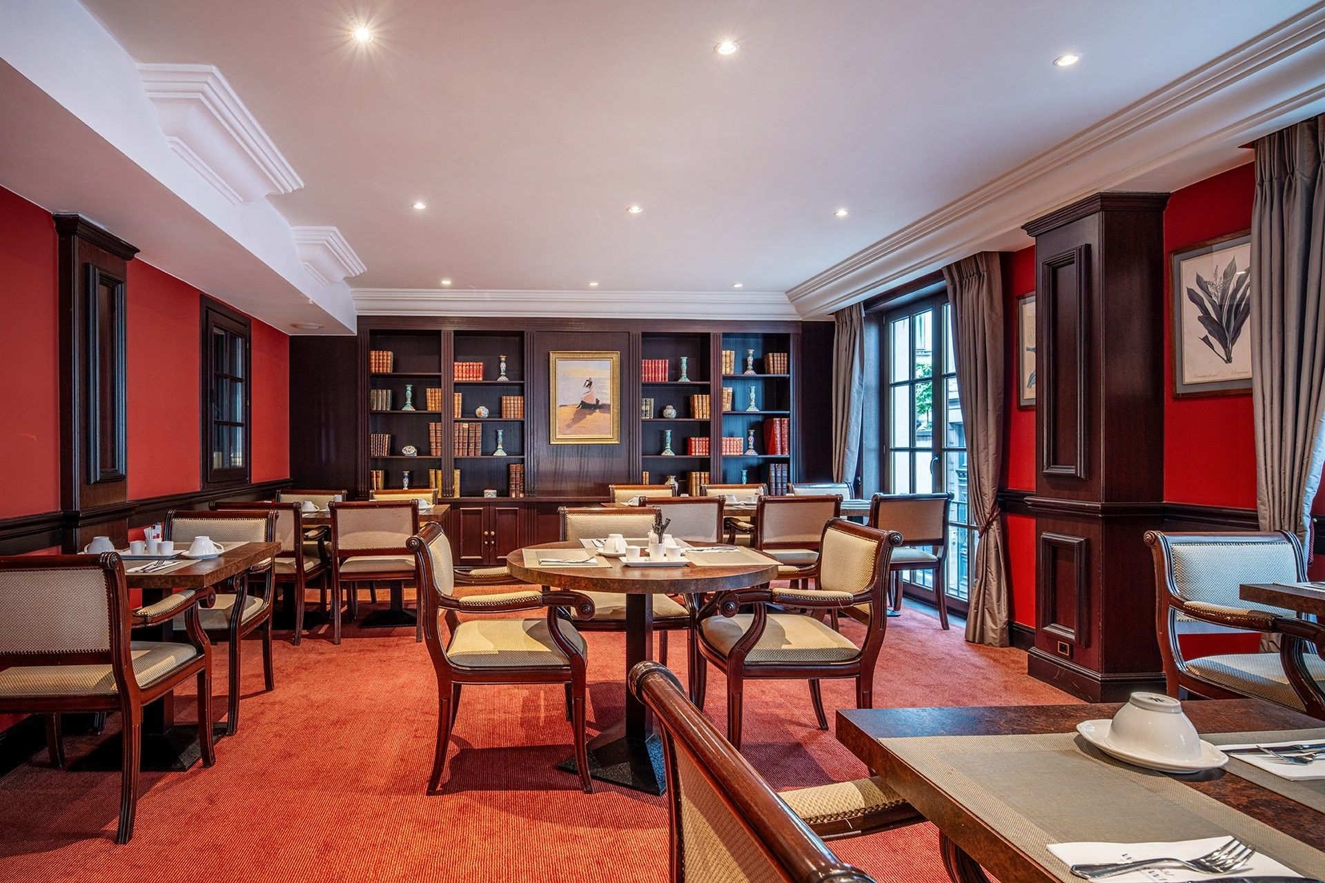 Salon Grand-Place breakfast room with tables arranged by bookshelves under red walls at Warwick Grand-Place Brussels