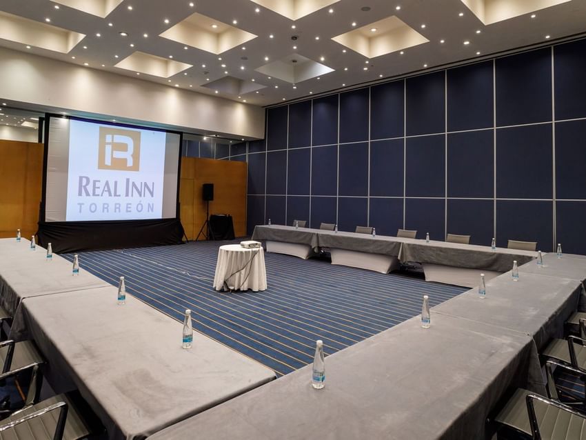 Chicago large conference setup showing a U-shaped table arrangement and a large branded projector at Real Inn Torreon