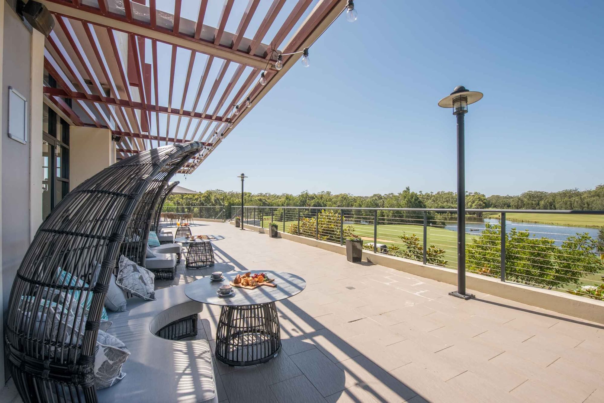 Karinyas terrace with modern furniture overlooking a tranquil lake at Mercure Kooindah Waters