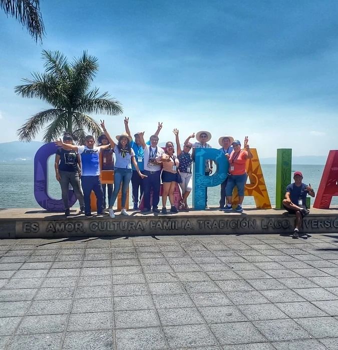 Un grupo de personas posando delante de un gran cartel cerca de One Hotels