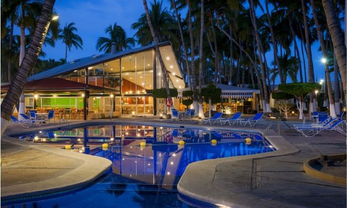 Pool with sunbeds & hotel exterior at Araiza Hotel Palmira