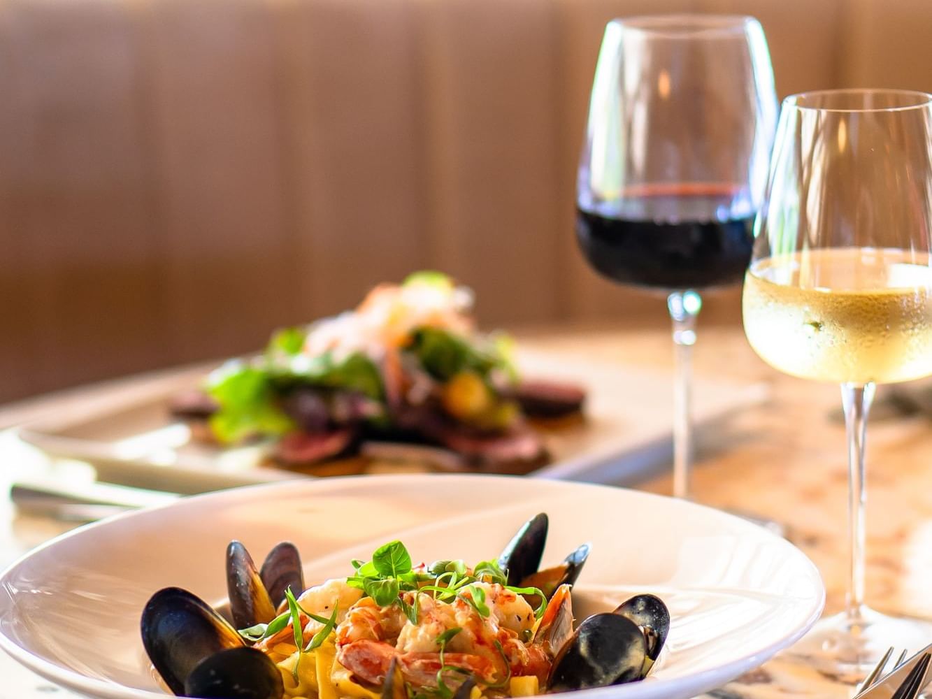 Gourmet pasta dish with mussels and shrimp, paired with red and white wine, served in Breeze Restaurant at Golden Rock Resort