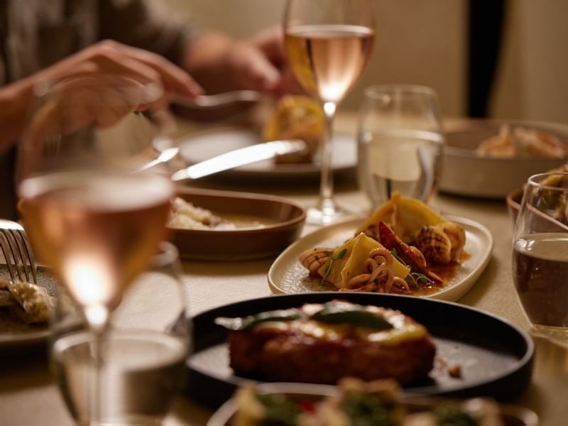 Close-up of dinner setting with wine glasses & dishes in Modo Mio at Crown Promenade Perth