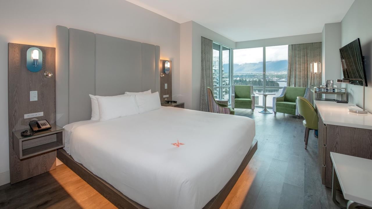 Hotel room with a large bed, seating area, and stunning views.