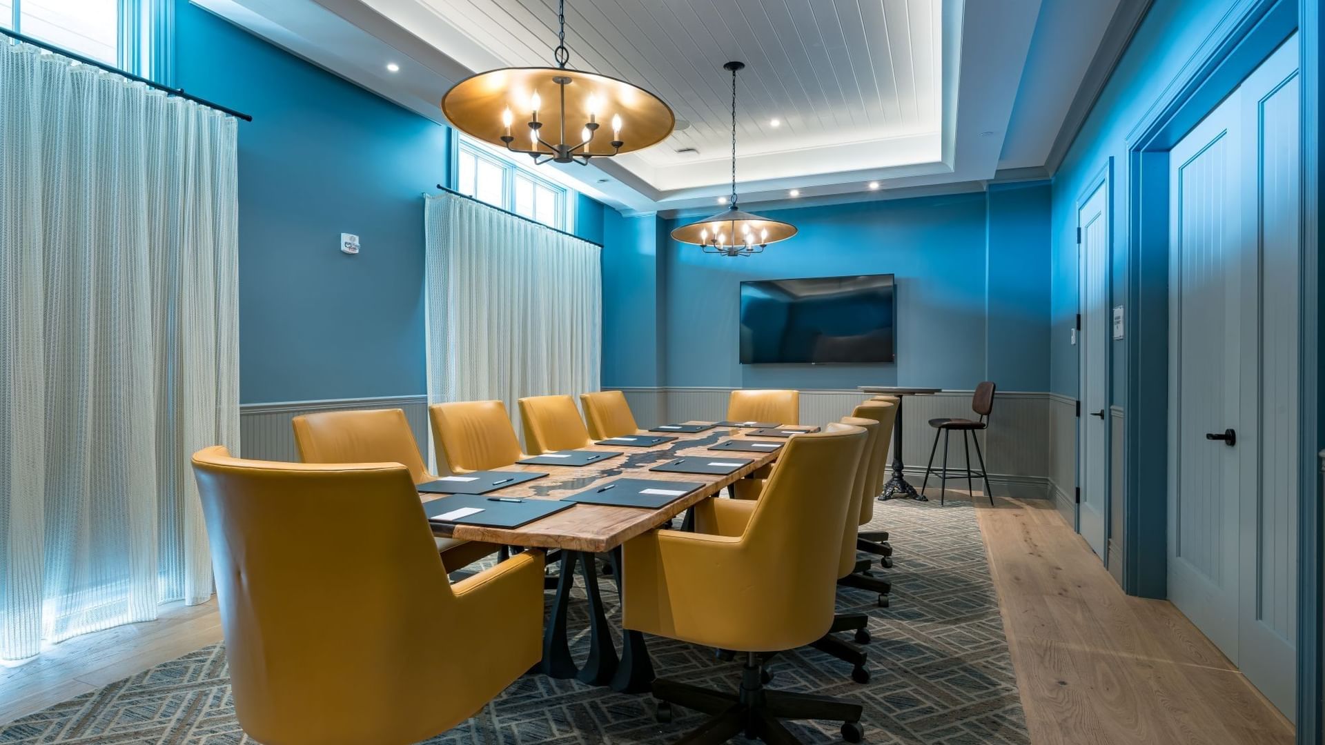 Boardroom with blue walls, yellow leather chairs, and modern lighting at Camp Creek Inn in Inlet Beach