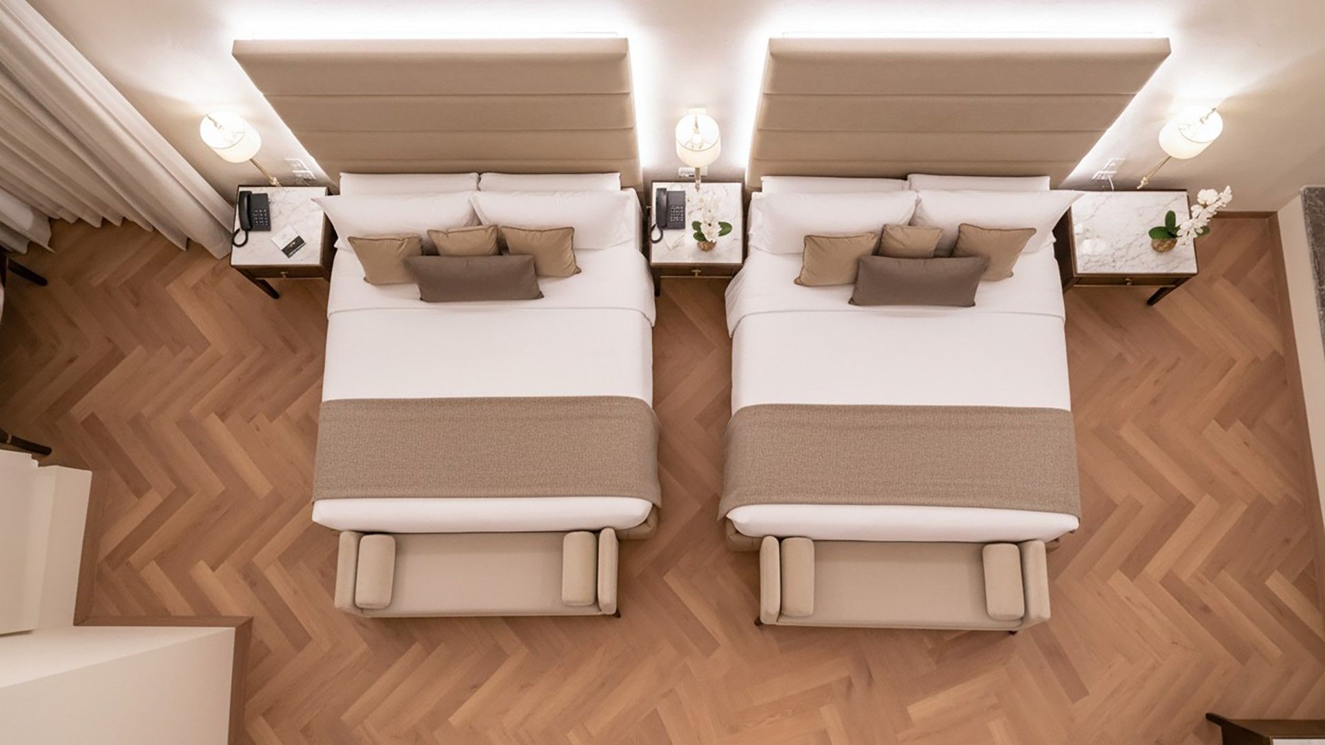 Overhead bird's-eye view of two beds with tan linens and herringbone wood floors in Two Queen Premium at Quinta Real Puebla