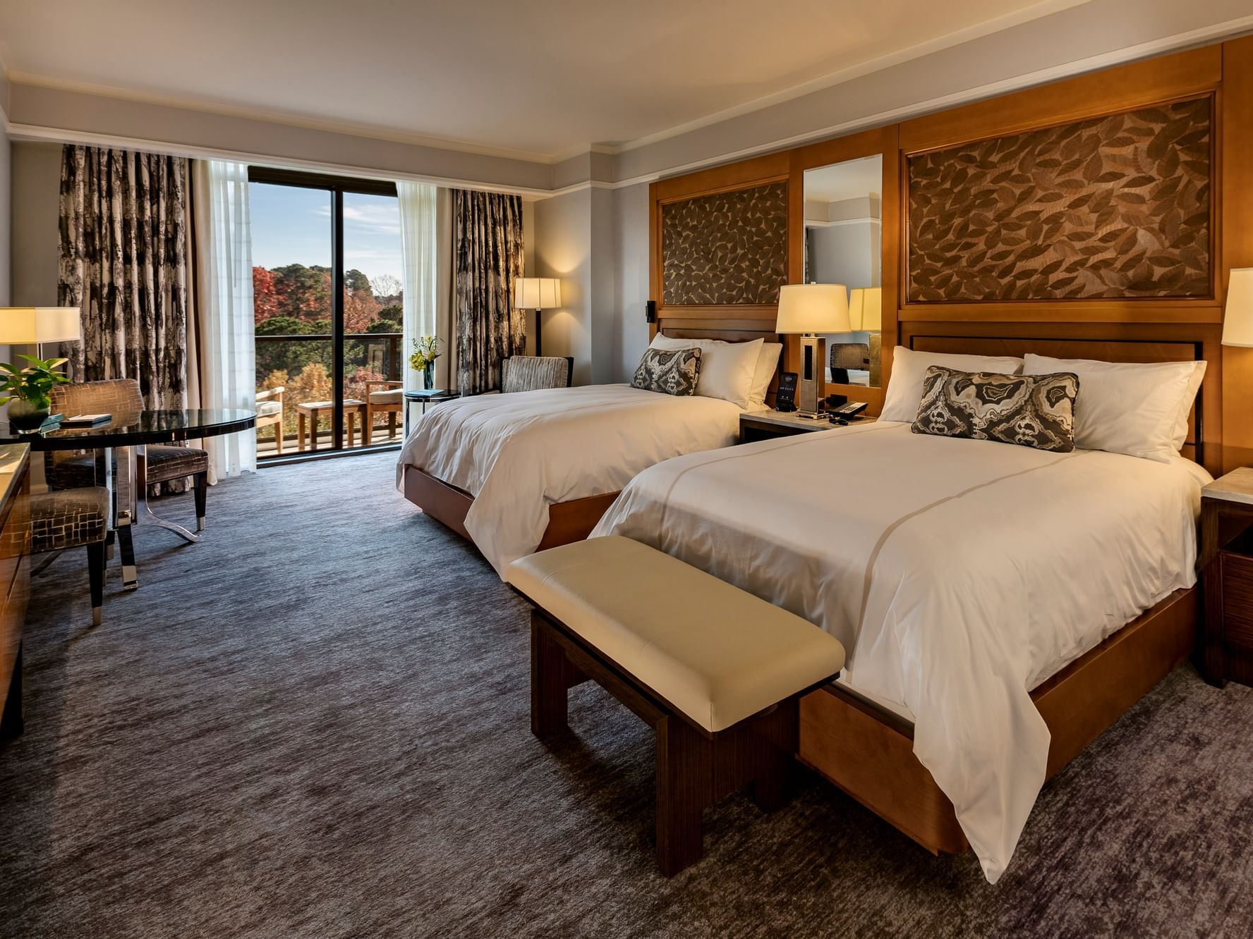 Twin beds & cozy interior in Lake View Balcony Room with carpeted floors at The Umstead Hotel and Spa