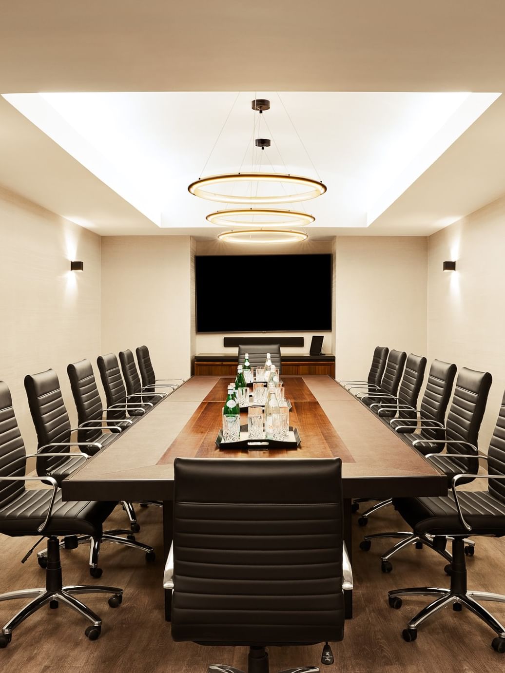Executive Boardroom with long wooden table, black leather chairs, and wall-mounted screen at Gansevoort Meatpacking NYC - NEW