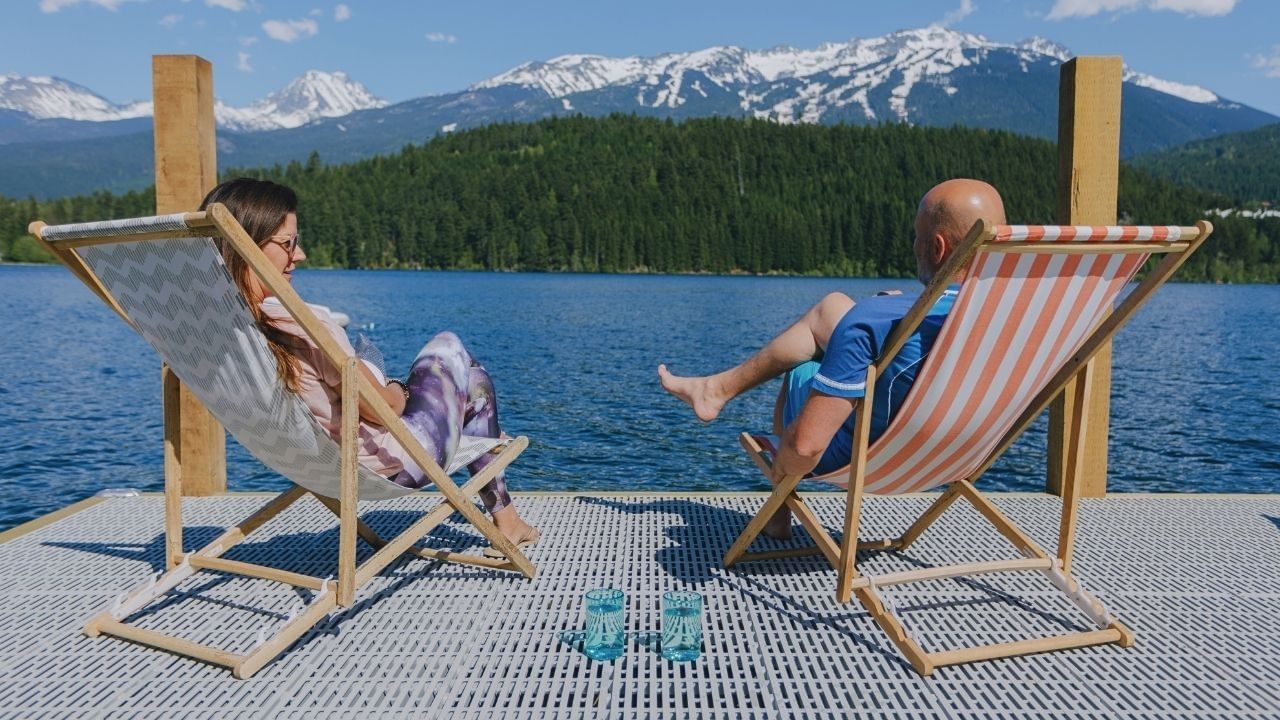 Couple relaxing on lounge chairs by a lake with mountain view in blog post.