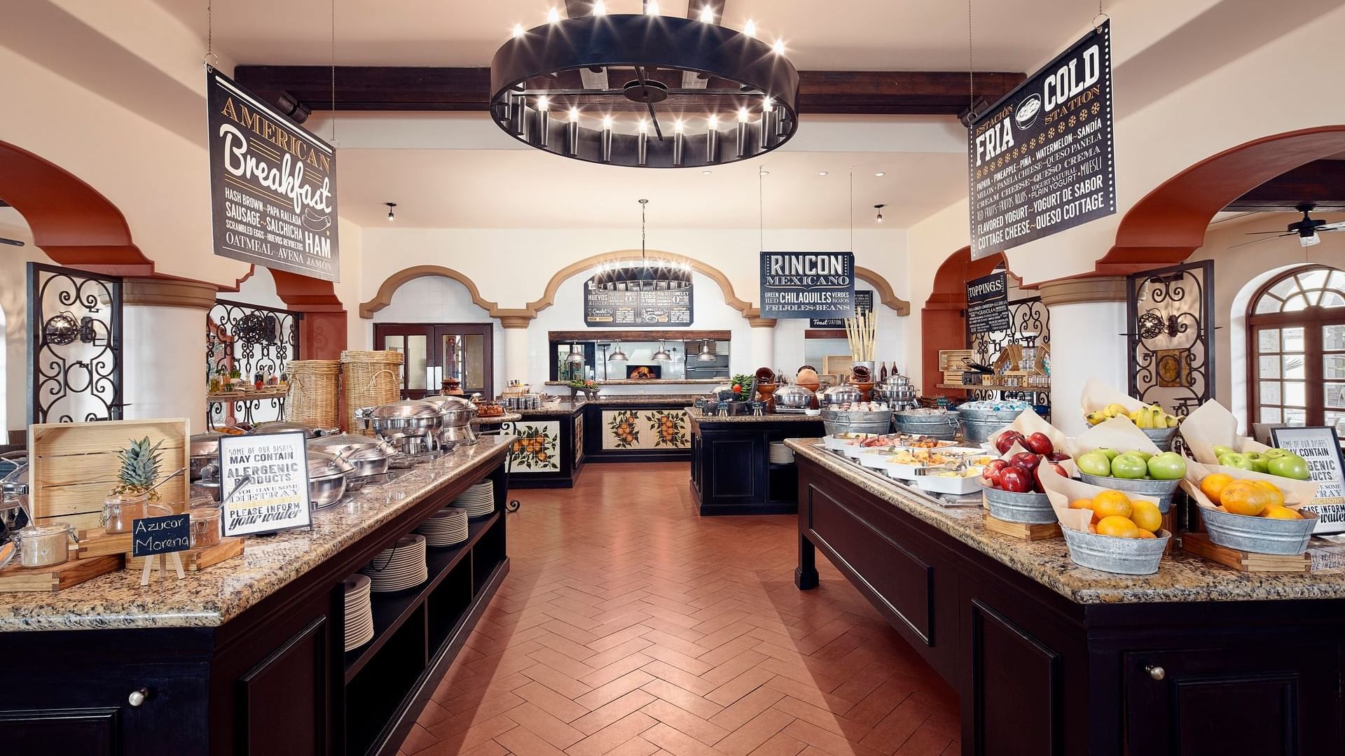 Tomates grand breakfast buffet area with multiple food stations under a large chandelier at Hacienda Del Mar Los Cabos.