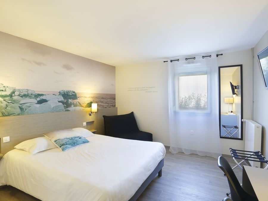 Queen bedroom with a comfy chair at Hotel Au Chene Vert
