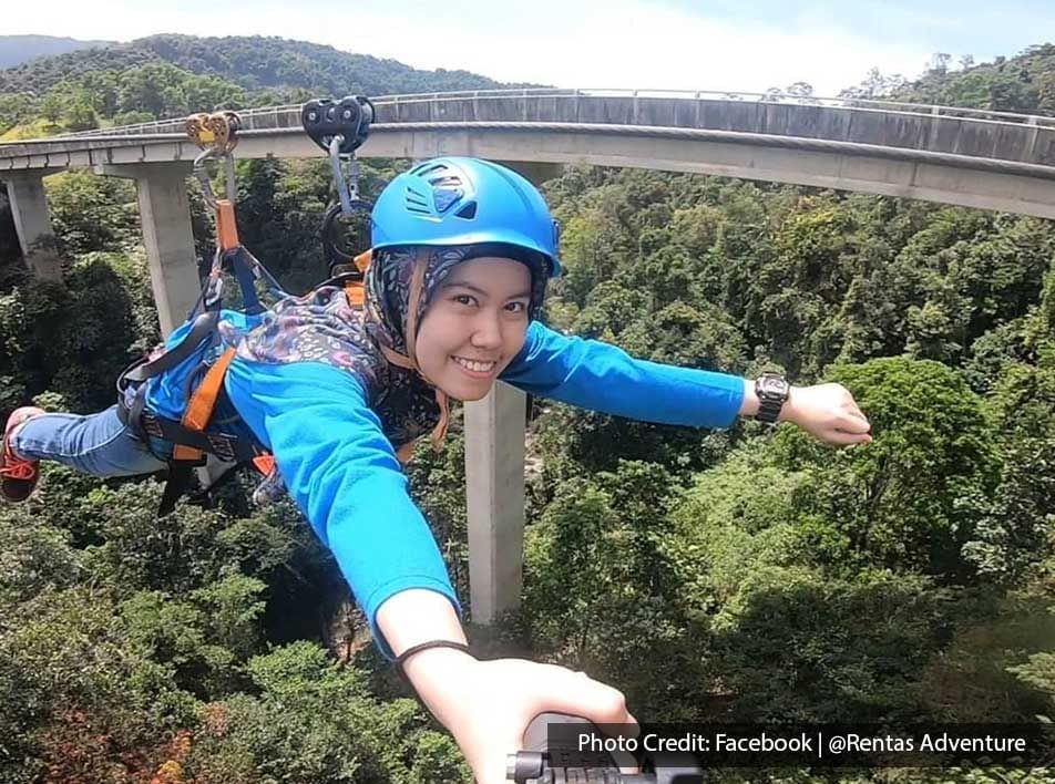 A woman was taking a selfie while zip-lining through a forest - Lexis Suites Penang