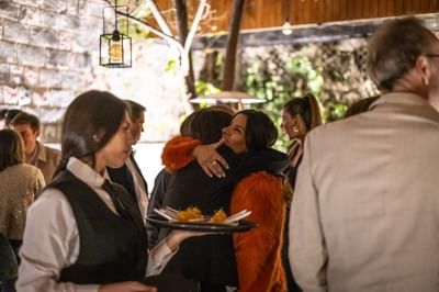 Invitados abrazándose y personal llevando aperitivos en The Aubrey, hoteles con restaurante en Santiago