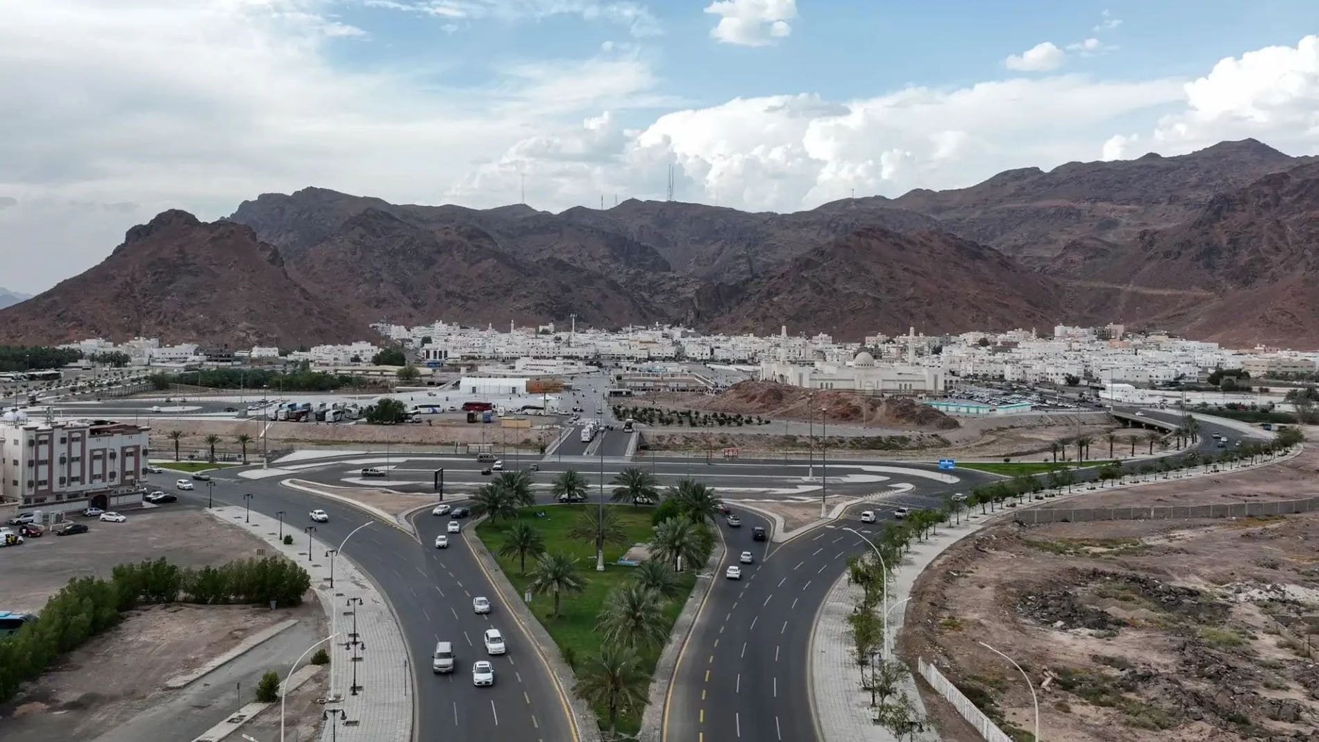 Aerial view of Mount Uhud with palm trees & mountains, and white buildings at Saja Warwick Madinah