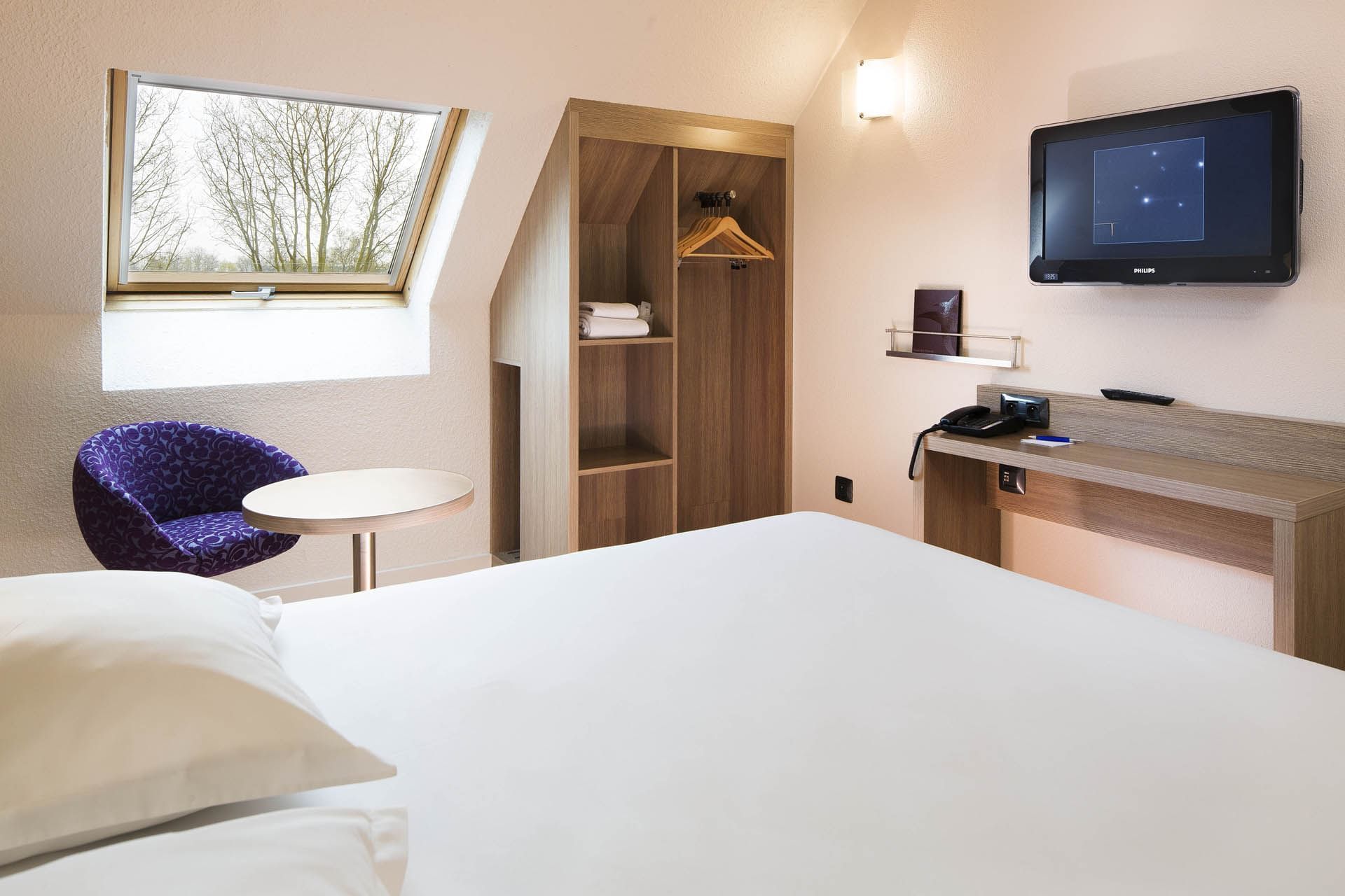 Lit king-size et salon dans une chambre à l'Escale Oceania Orléans