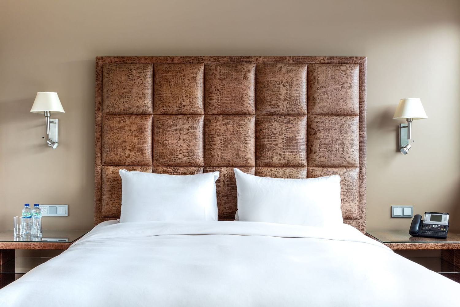 Close-up of a comfy bed with side tables and wall lamps in a room at The May Fair Hotel