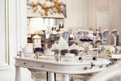 Elegant tea service on a white cart, featuring a silver kettle and various tea jars in Park Lounge at Park Hyatt Saigon