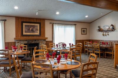 Cozy dining room at The Ranch at Ucross, with round tables set for dinner and rustic western decor