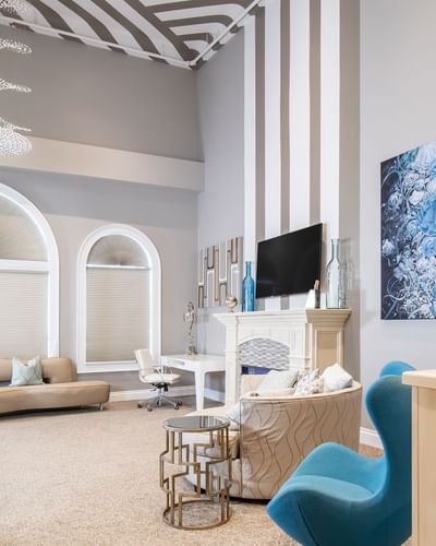 Comfy chairs, TV, striped wallpaper & fireplace in living area of Presidential suite at Retro Suites Hotel