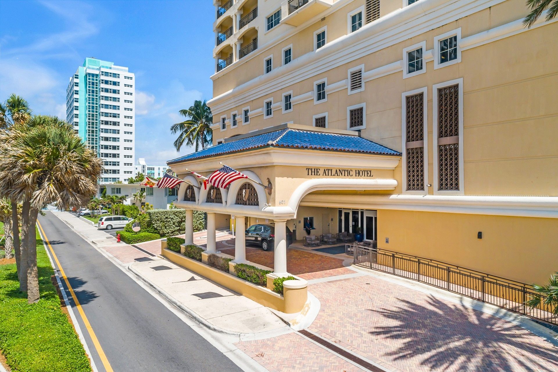 The main entrance of The Atlantic Hotel with a yellow building, blue roof, and white columns.