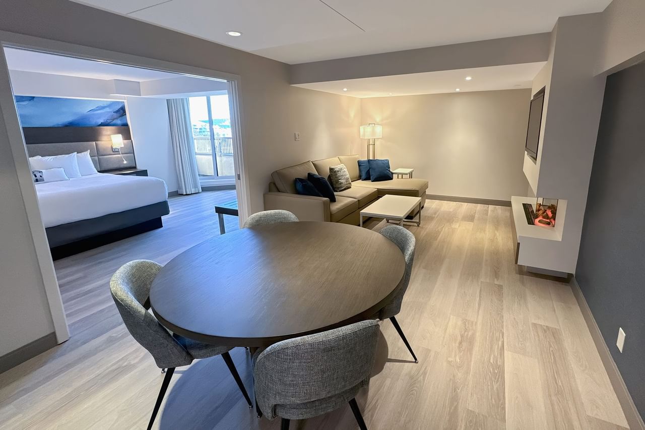 Hotel guestroom with round table, four chairs, a sofa and a bedroom