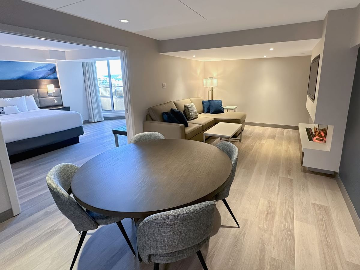 Hotel guestroom with round table, four chairs, a sofa and a bedroom