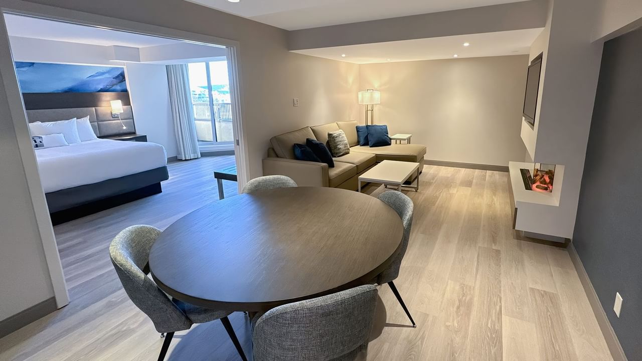 Hotel guestroom with round table, four chairs, a sofa and a bedroom
