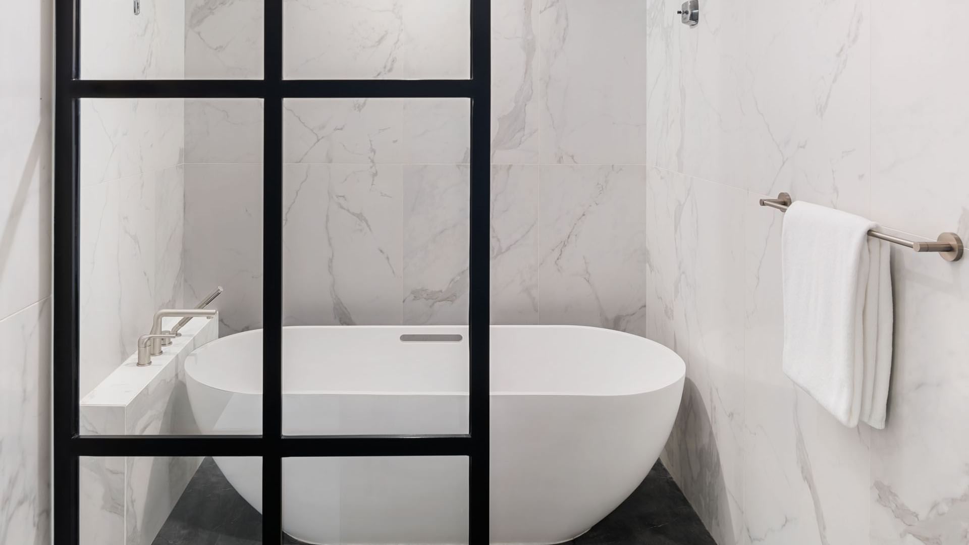 Modern hotel bathroom with a freestanding bathtub and marble tile walls at Paramount Hotel Midtown