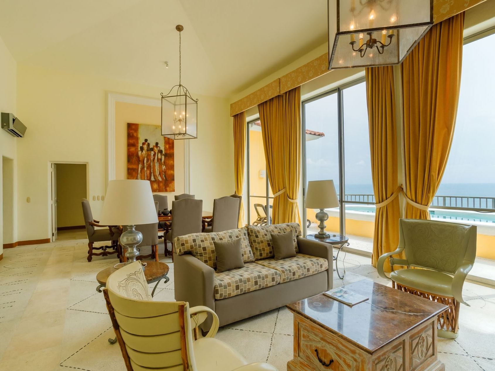 King Presidential Suite with a modern sofa, dining area, and large windows facing the ocean at Quinta Real Acapulco
