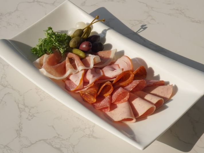 Sliced assorted meats served with olives Chatrium Hotels