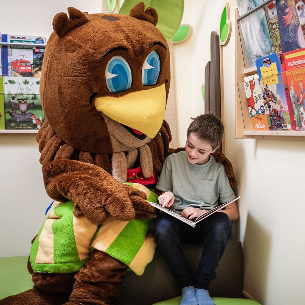 Junges Kind liest mit einem Maskottchen im Kinderzimmer bei Ostermagie im Lido