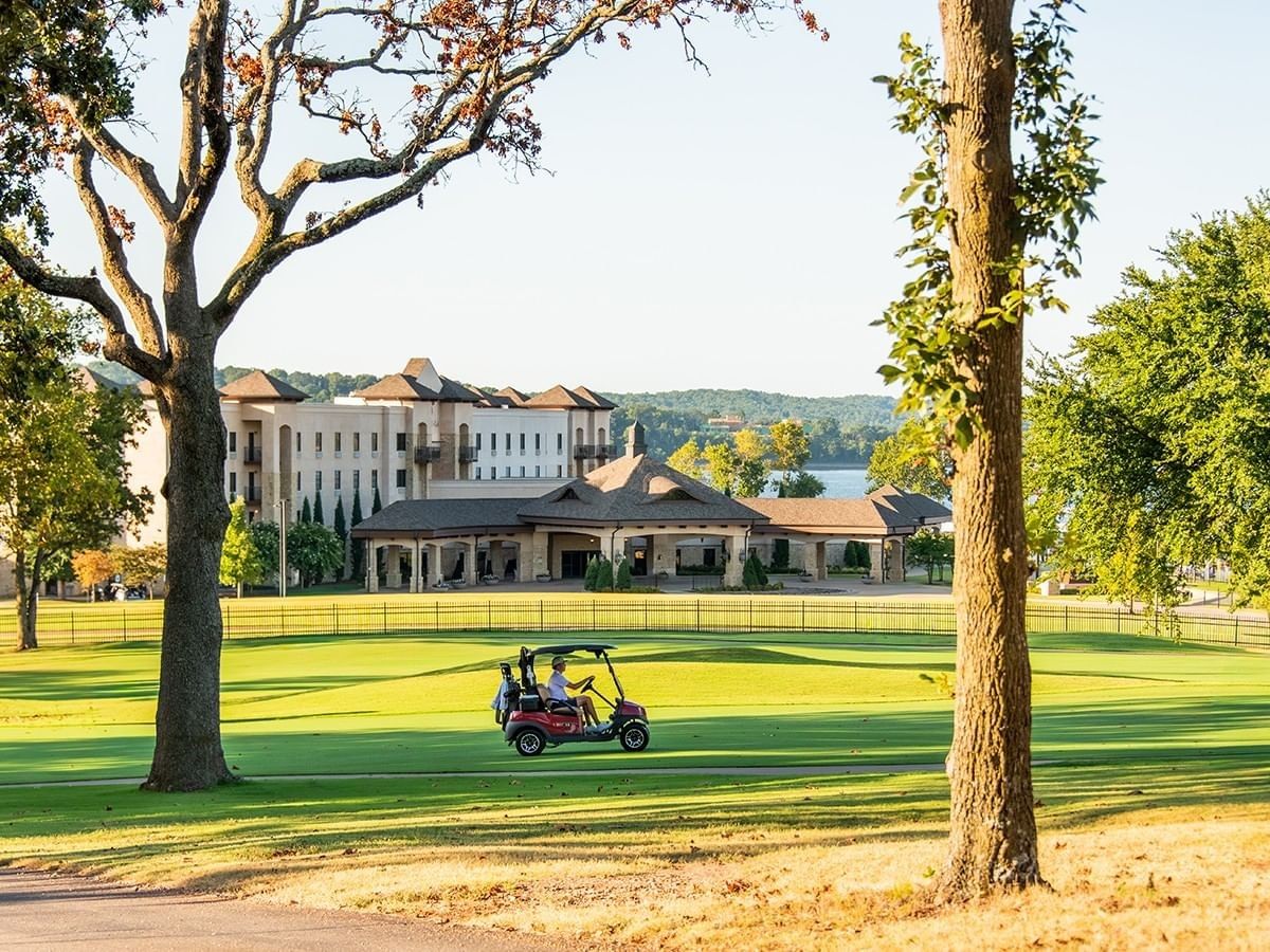 Guest driving a red golf cart on the lush green course at Shangri-La Resort and Golf Club at sunset
