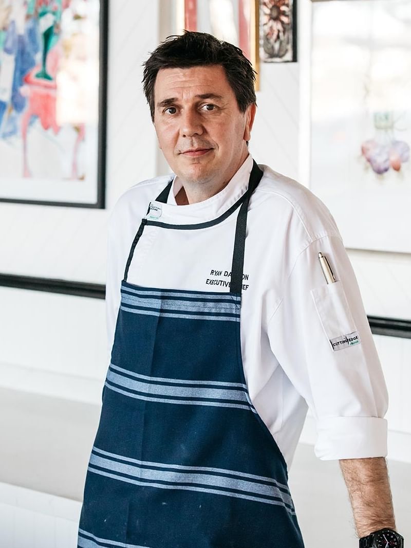 Bistro Manly at Elysium Manly, featuring a chef in an apron by framed art under bright lights surrounding a wall