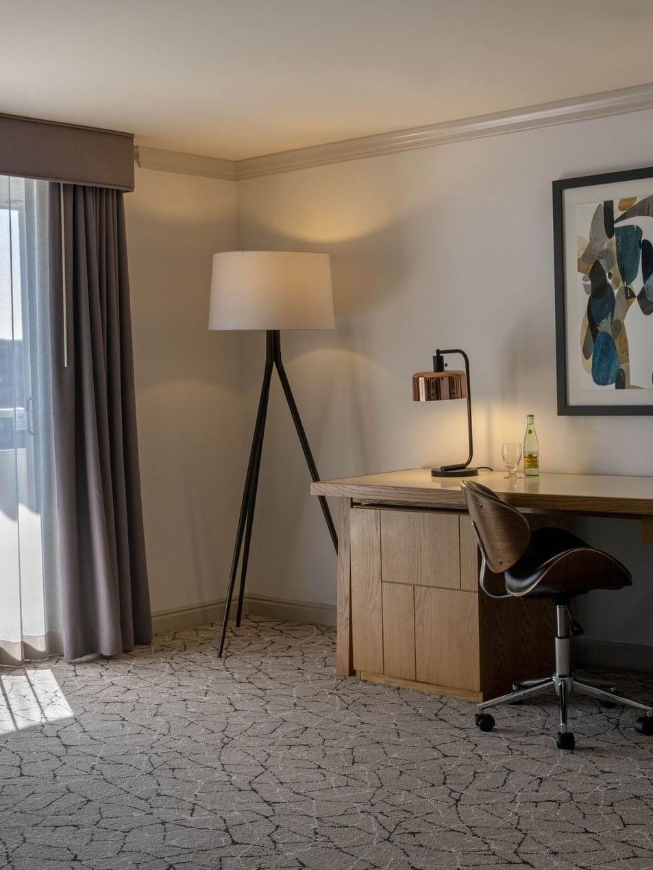 Modern desk with a chair and lamps by a tripod floor light under framed art in Premier Junior Suites at Warwick Denver