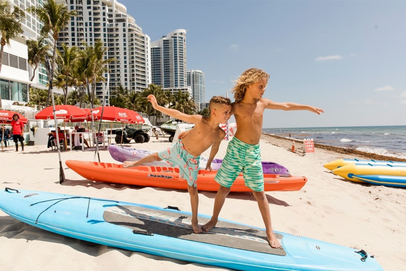 2 kids on a paddleboard on the beach near The Diplomat Resort