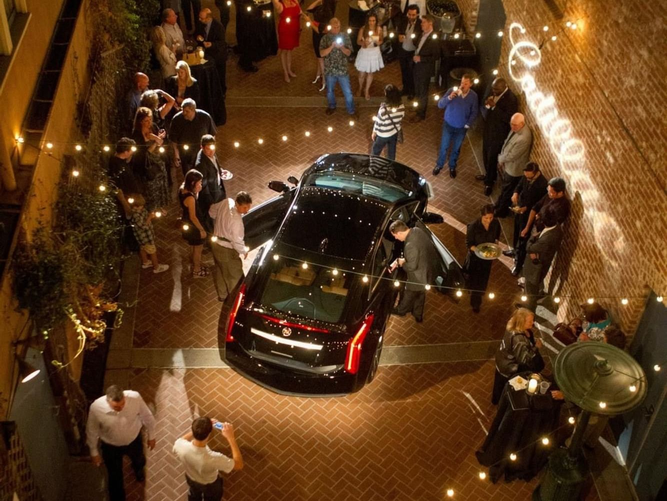 Aerial view of a black car with people and string lights in Copley Alley at Horton Grand Hotel