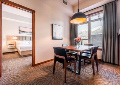 Dining table by the window and the entrance to the bedroom in One Bedroom Mountain View Suite at Blackstone Mountain Lodge