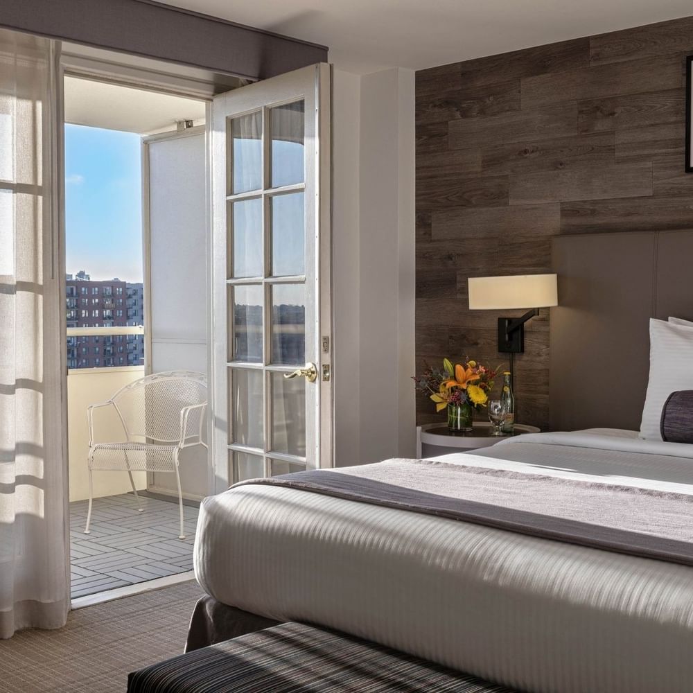 White balcony chair by a glass door in a guestroom with a wood wall in Executive Suites at Warwick Denver