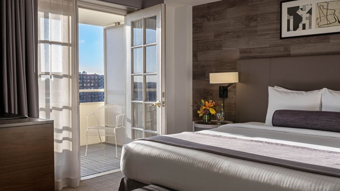 White balcony chair by a glass door in a guestroom with a wood wall in Executive Suites at Warwick Denver