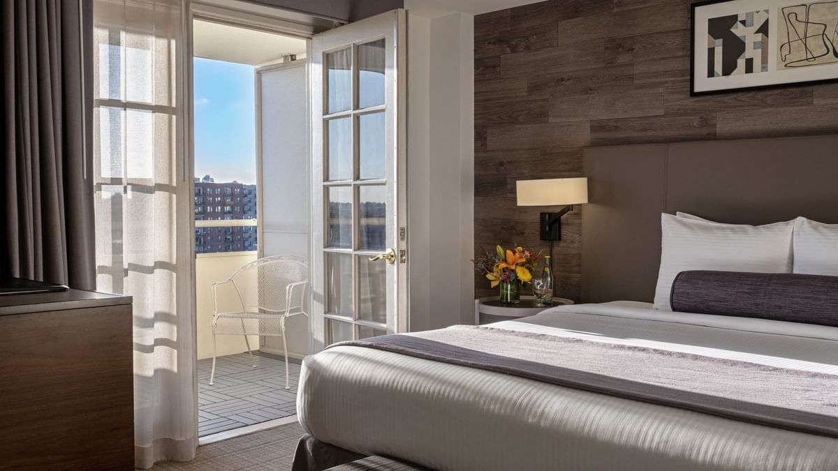 White balcony chair by a glass door in a guestroom with a wood wall in Executive Suites at Warwick Denver