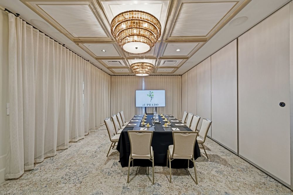 meeting room set up at el PRADO with a screen at the end of the table reading el PRADO with a yellow flower