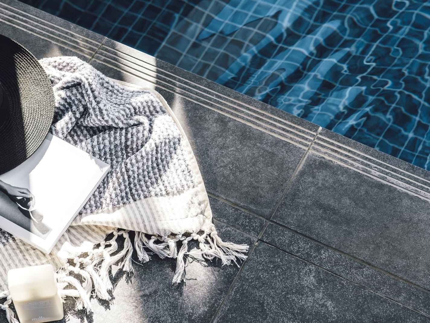 Close-up of blanket, book & hat by the pool at Como Melbourne
