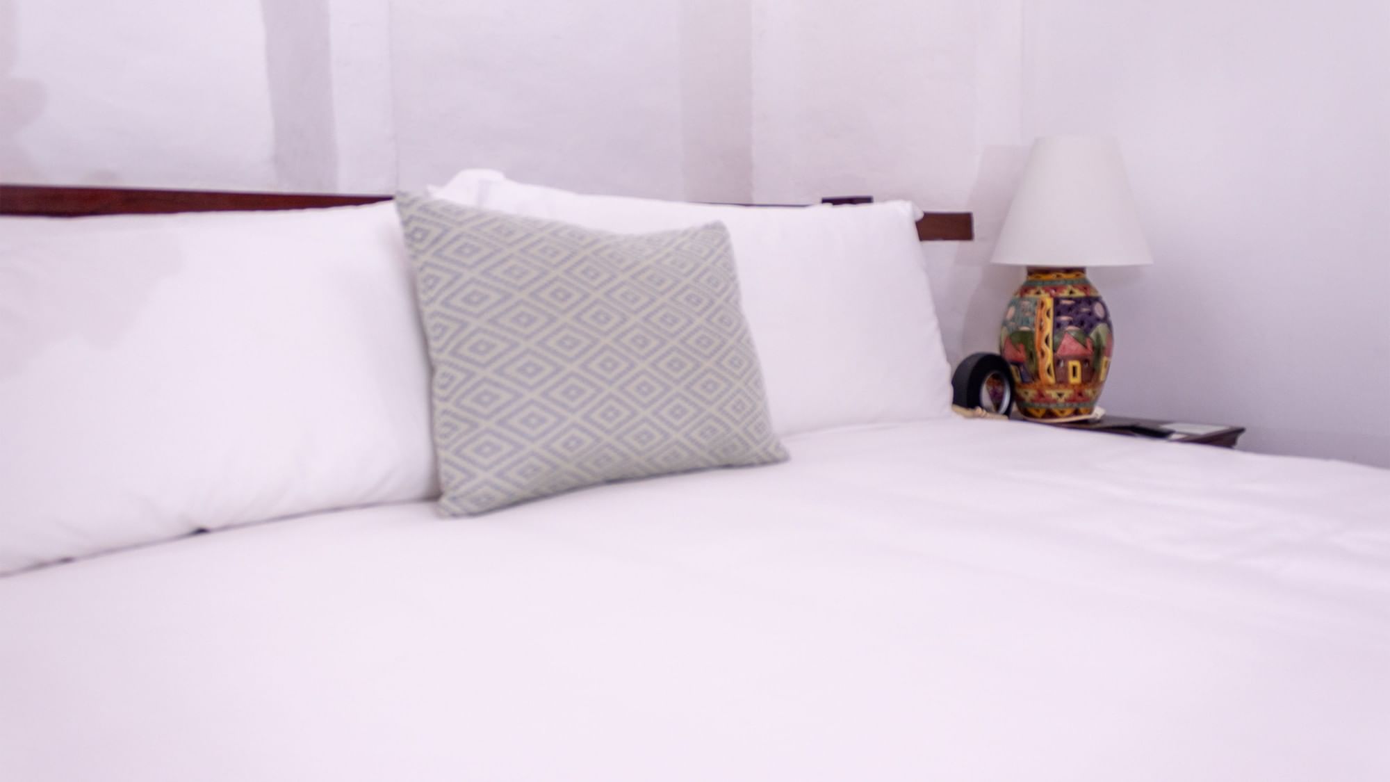 Cama king con ropa de cama blanca y almohada gris en la habitación superior del hotel Quinta Real Oaxaca en Oaxaca de Juárez