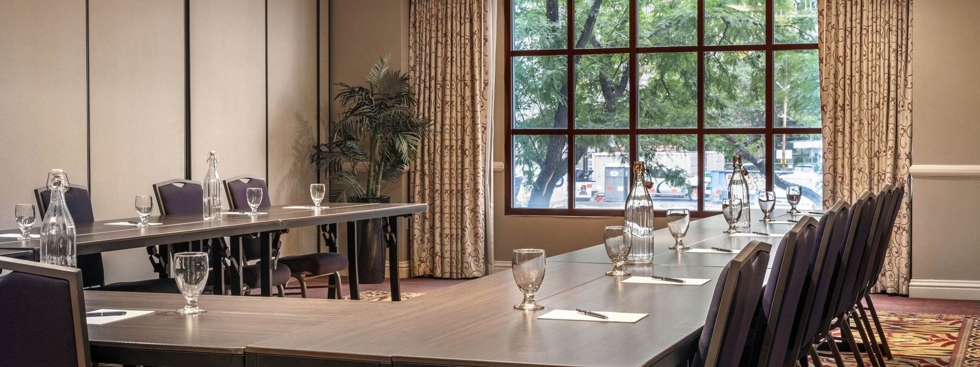 Long wooden tables in a U-shape by a large window with city views in Capitol I, II or III at Warwick Denver