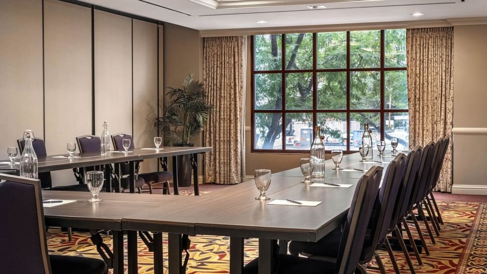 Long wooden tables in a U-shape by a large window with city views in Capitol I/II/III at Warwick Denver