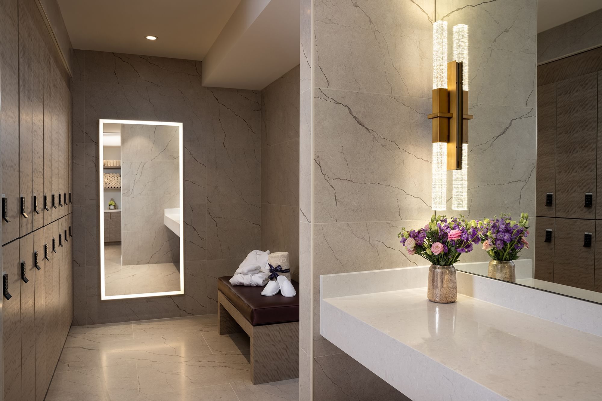 Changing room featuring marble walls and elegant lighting at Le Spa by Warwick Melrose