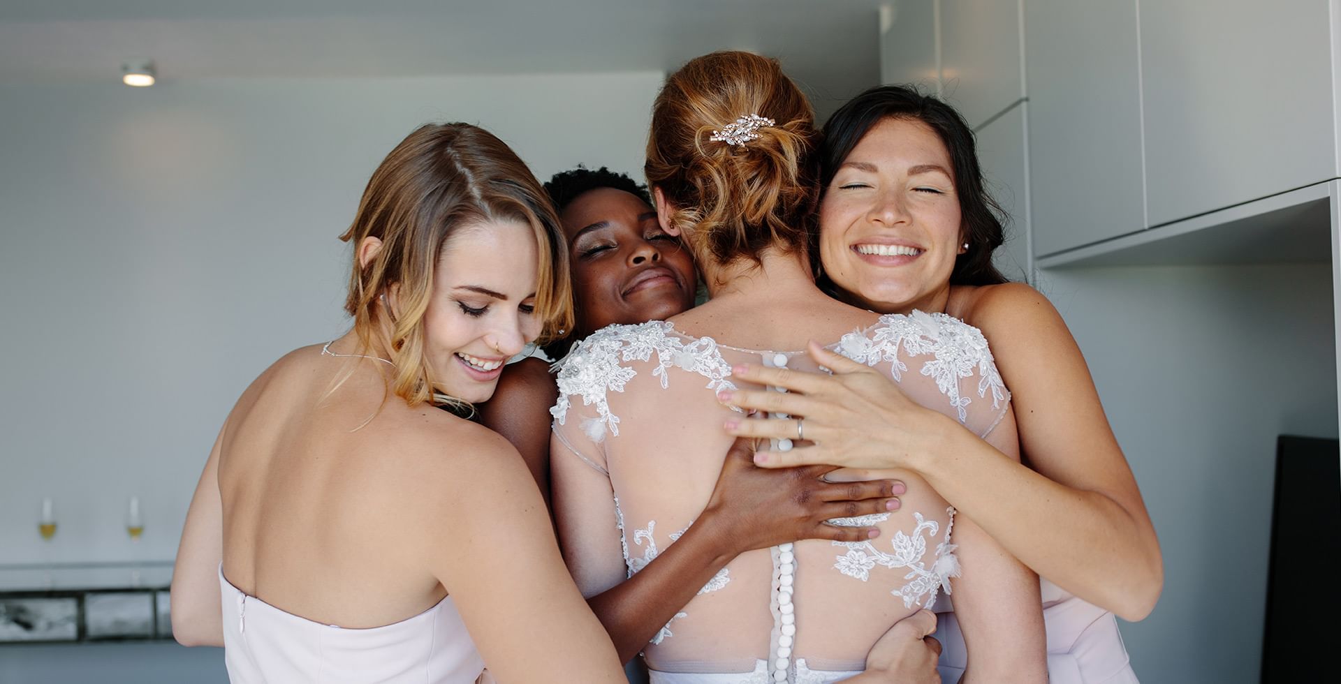 Bride & bridesmaids hugging each other in a wedding venue at Eldorado, a Coast Hotel