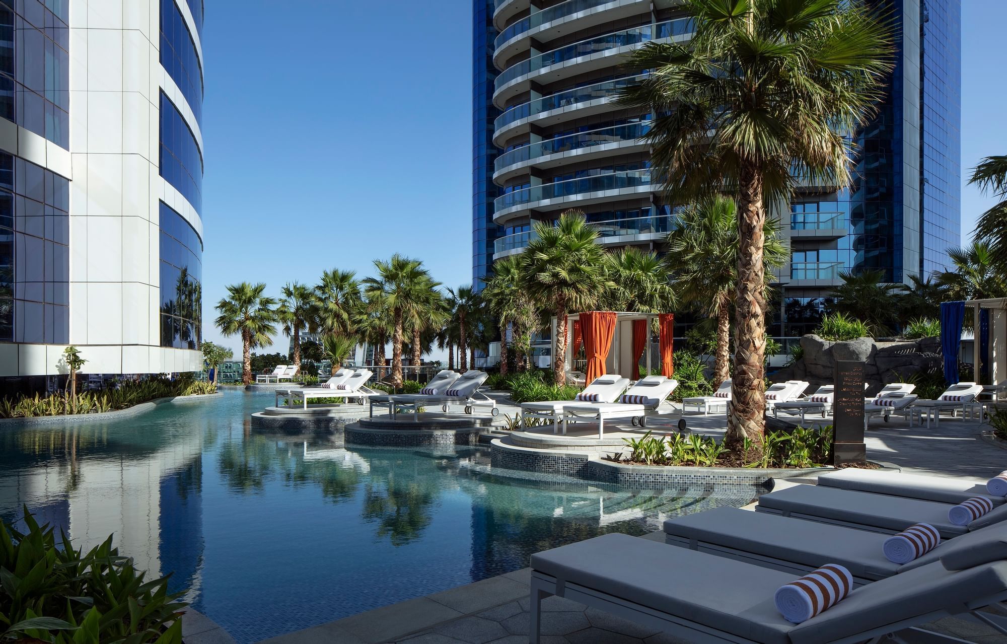 Sun lounges and outdoor pool surrounded by palm trees at Paramount Hotel Dubai