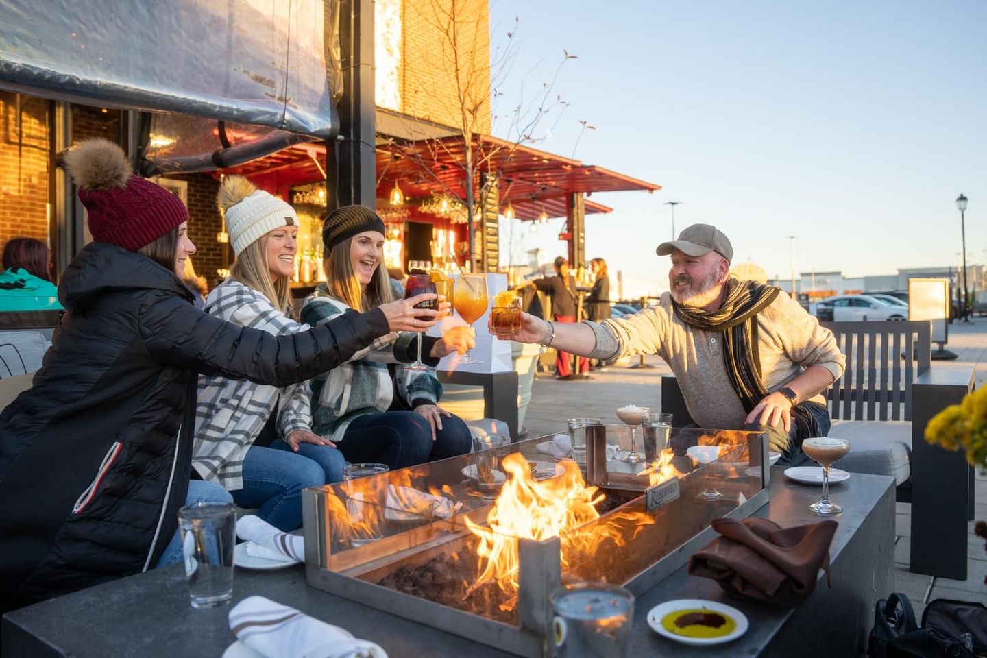 Friends toasting beer by a fireplace in Tuscan Market at The Artisan Hotel at Tuscan Village