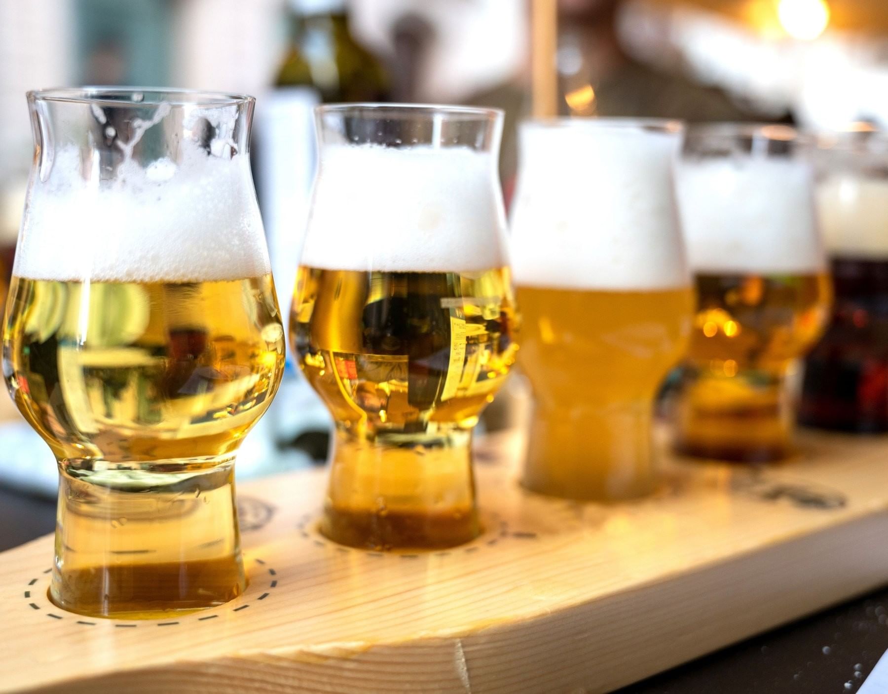 Four glasses of craft beer on a wooden flight paddle at The Inn at Celebration, featuring activities in Celebration Florida
